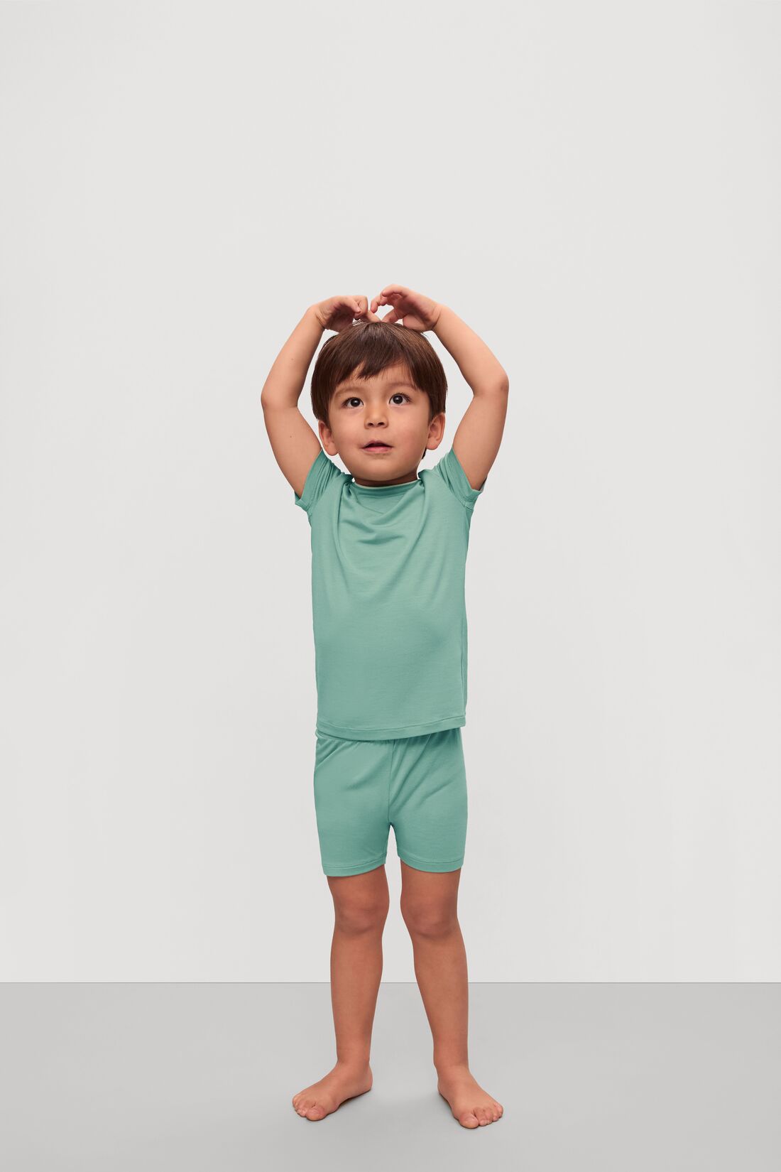 Model is wearing Kids TENCEL™ Modal Unisex Short PJ Set in Seagrass/White
