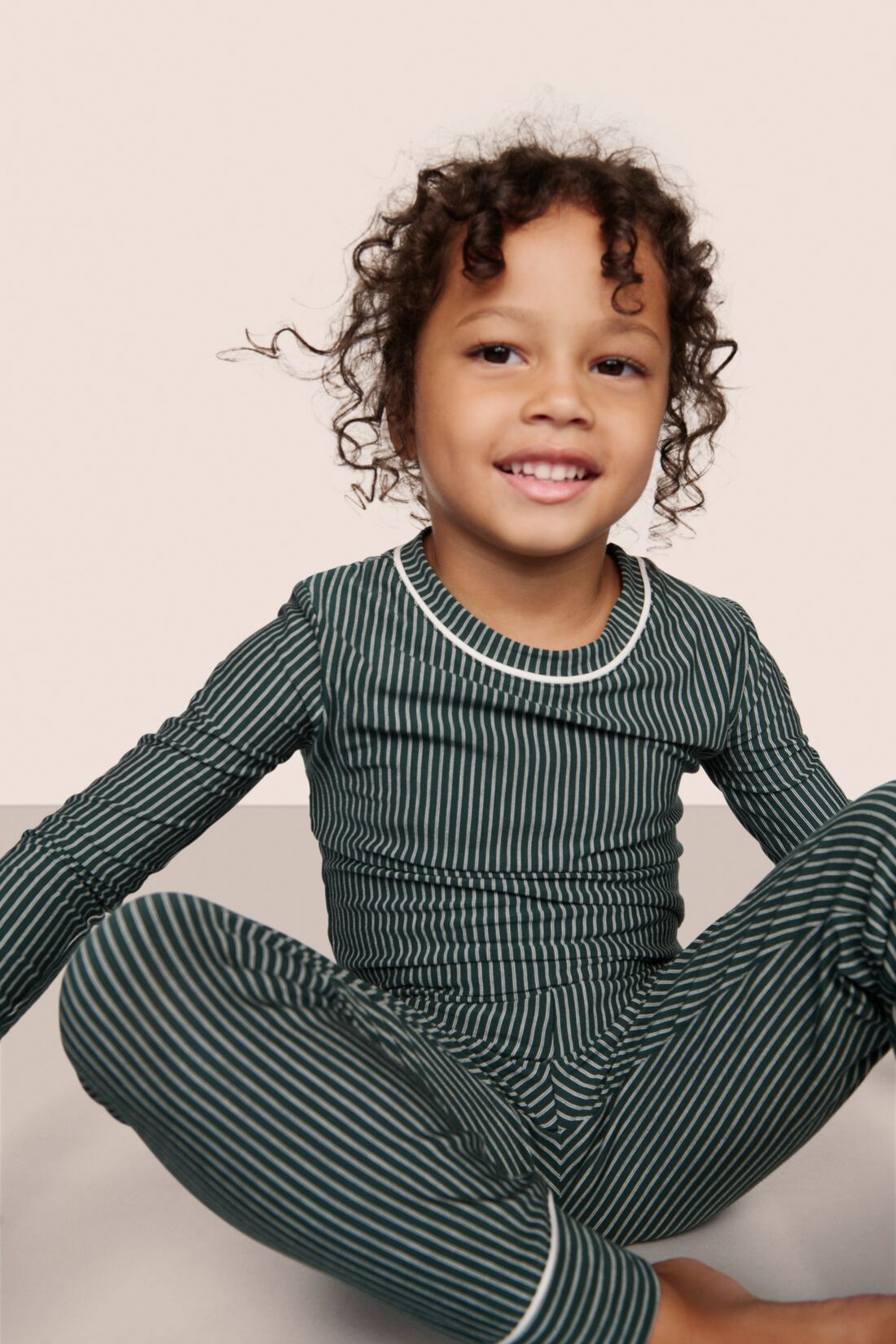 Model is wearing Kids Printed TENCEL™ Modal Unisex Long PJ Set  in Duo Stripe Pine/Ivory