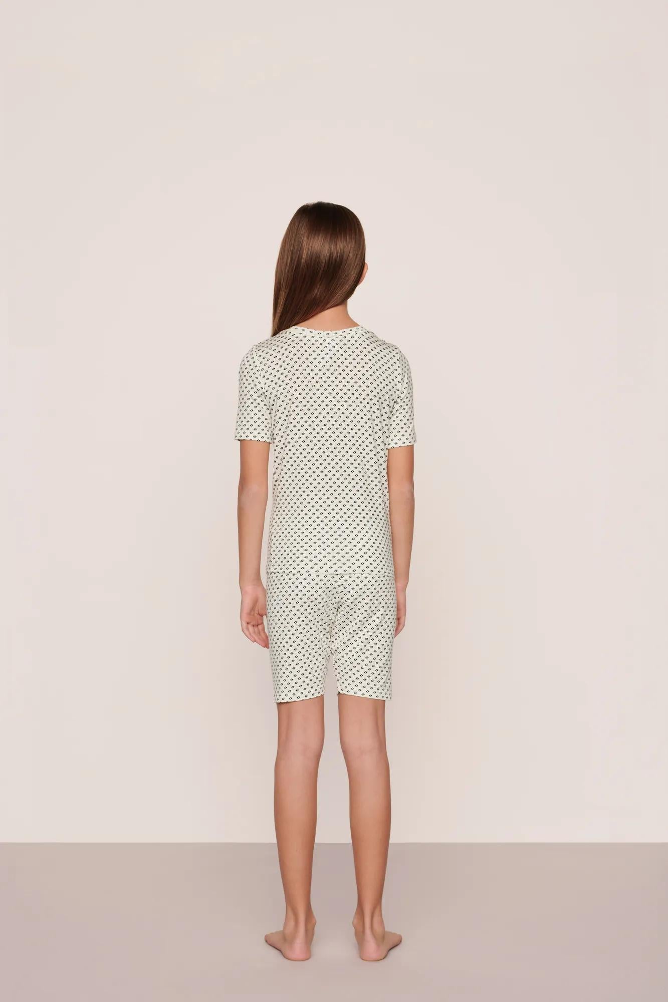 Model is wearing Kids Printed TENCEL™ Modal Unisex Short PJ Set in Tide Dot Ivory/Ivory