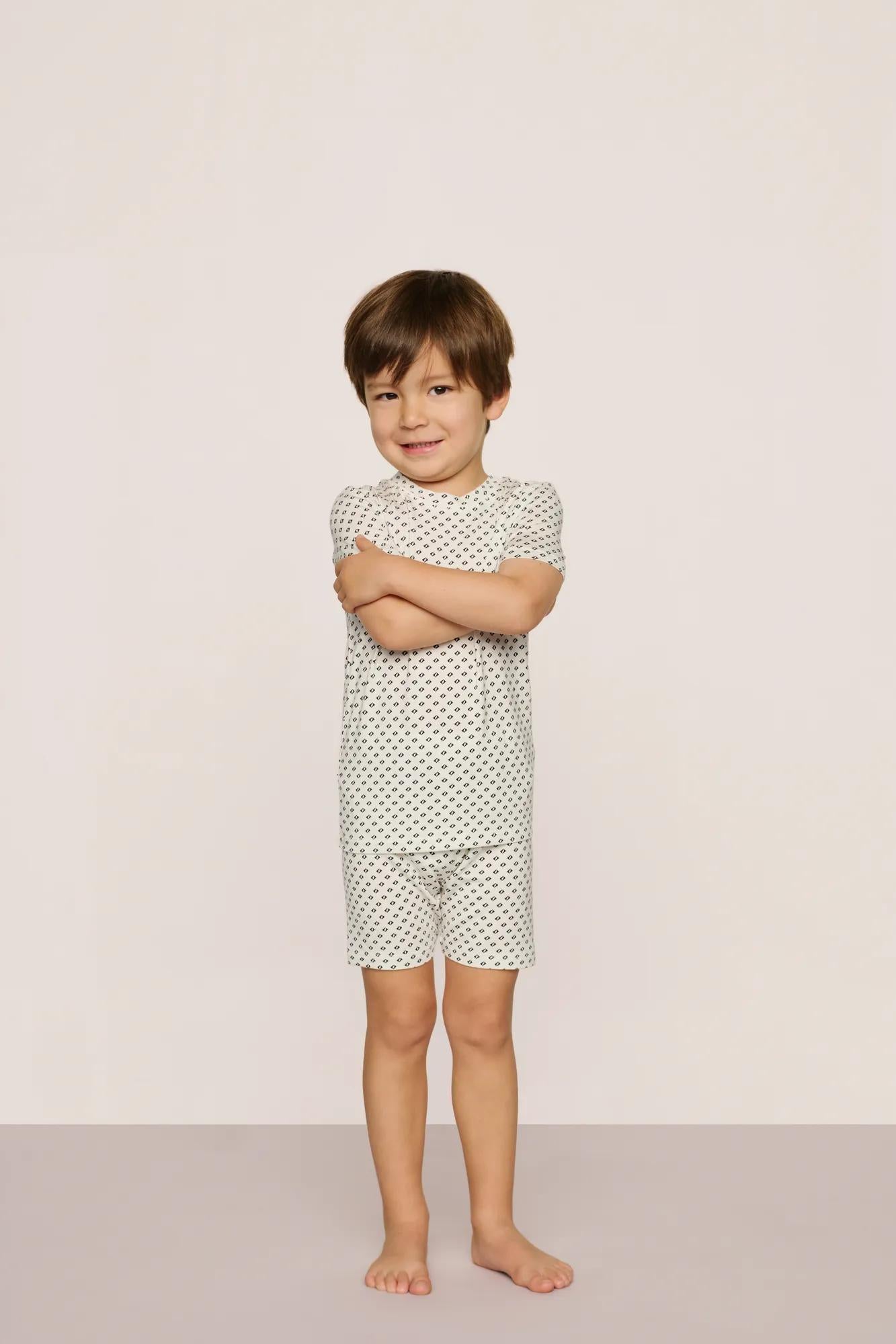 Model is wearing Kids Printed TENCEL™ Modal Unisex Short PJ Set in Tide Dot Ivory/Ivory