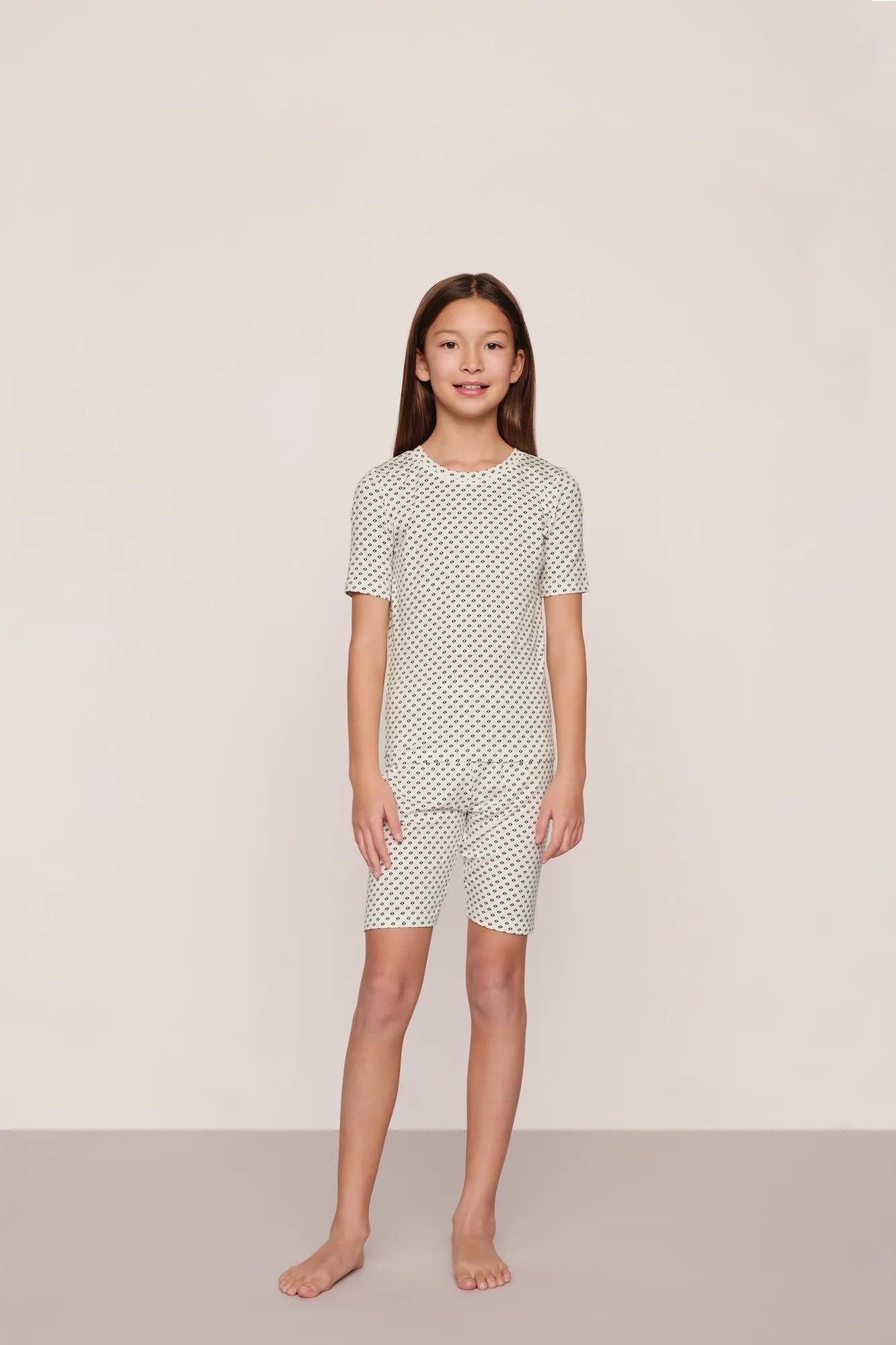 Model is wearing Kids Printed TENCEL™ Modal Unisex Short PJ Set in Tide Dot Ivory/Ivory